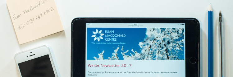 office items on a table with a tablet computer showing the Euan MacDonald Centre newsletter