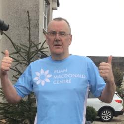 David Thomson, wearing a Euan MacDonald Centre T-shirt, is standing and giving both thumbs up