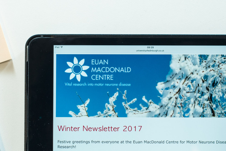 office items on a table with a tablet computer showing the Euan MacDonald Centre newsletter