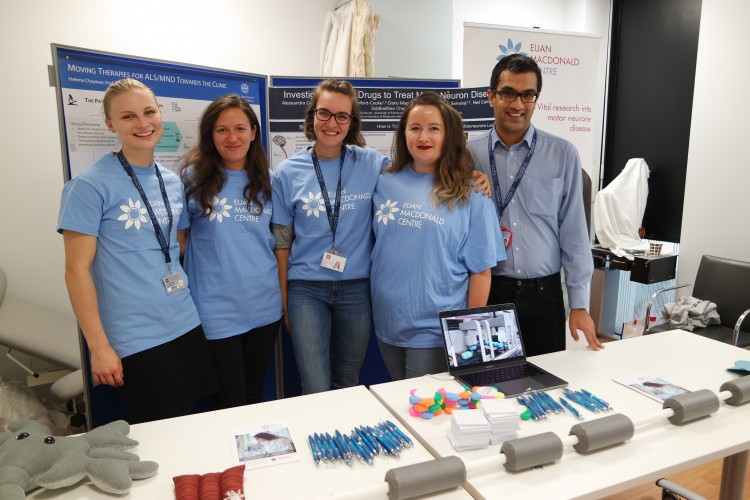 Group of Euan MacDonald scientists and researchers in Centre t-shirts, smiling at an open evening event.