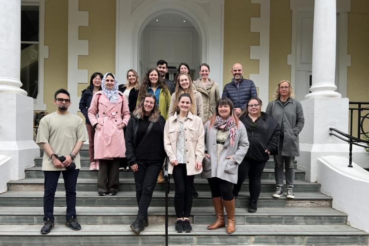 Group picture of researchers standing on stairs outside of a building