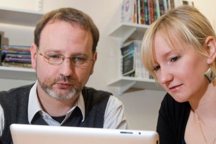 Two people in relaxed discussion looking at an iPad