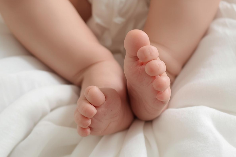 An image of baby feet on a soft white blanket