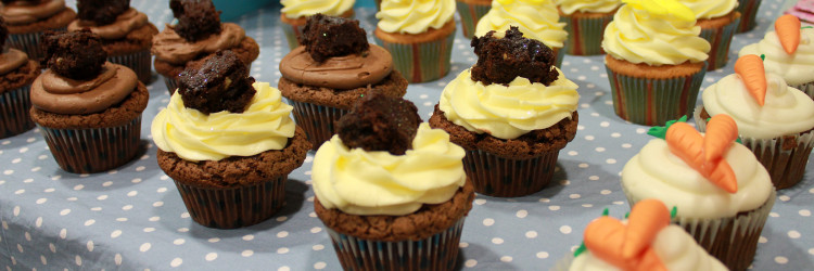 A close up of chocolate and carrot cake cupcakes on a blue polka dot table cloth at a bake sale raising funds for the Euan MacDonald Centre