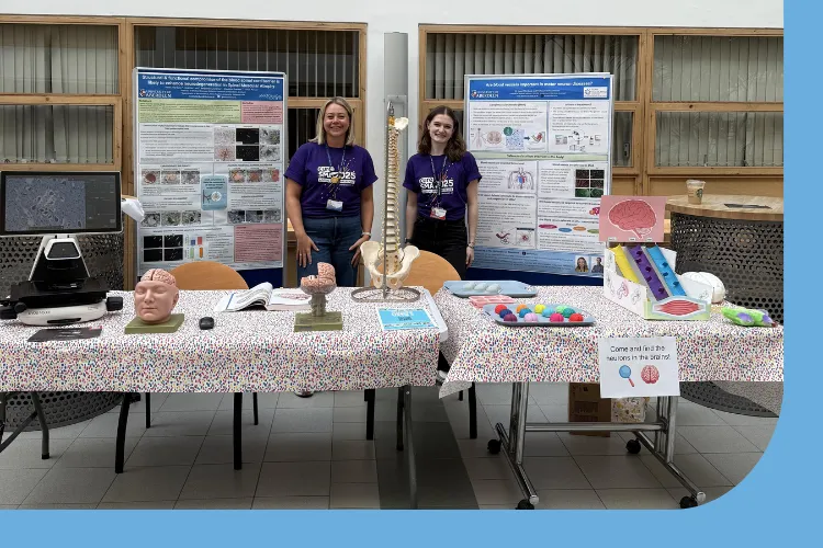 Hazel Allardyce and Ashley Donald at their research stand with microscope showing a healthy human spinal cord and a MND spinal cord where the motor neurons are lost. Models of the brain and spinal to show what is affected in MND. Playdoh brains with beads so children could interact, a model showing how the message from the brain/spinal cord and muscles is disturbed in MND made of 3 tubes, 1 hollow, 1 partly filled, 1 fully filled , using marbles to travel down the tubes or not in the 3rd MND model