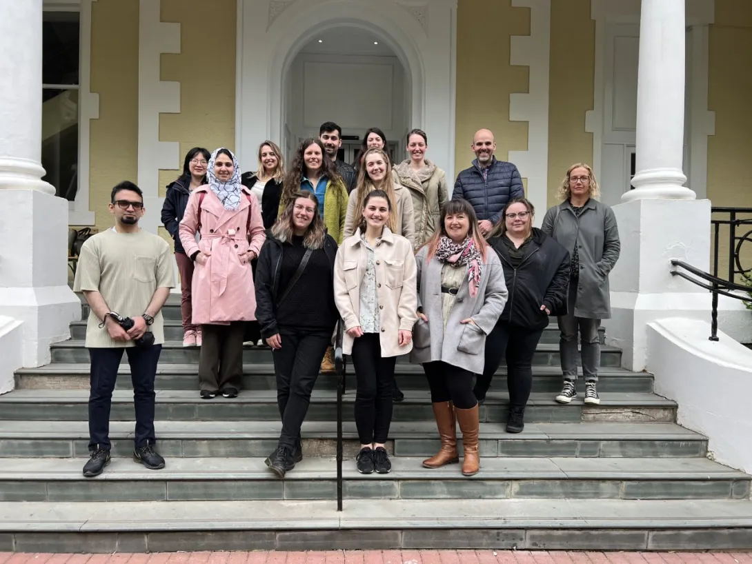 Group picture of researchers standing on stairs outside of a building