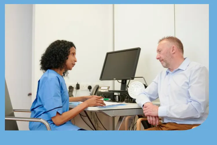 A picture of a nurse in uniform talking to a patient in a consulting room.